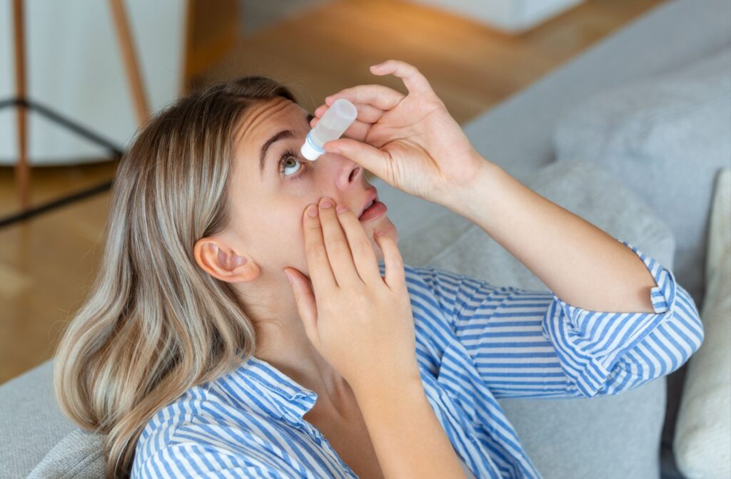 An adult puts contact lens-safe eye drops in their eyes to help alleviate and prevent more dry eye symptoms.